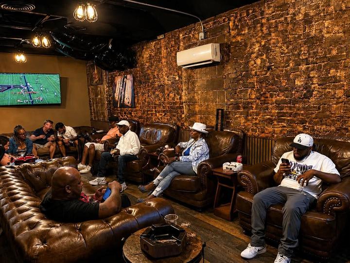Guests relaxing in leather chairs inside The Livery cigar lounge